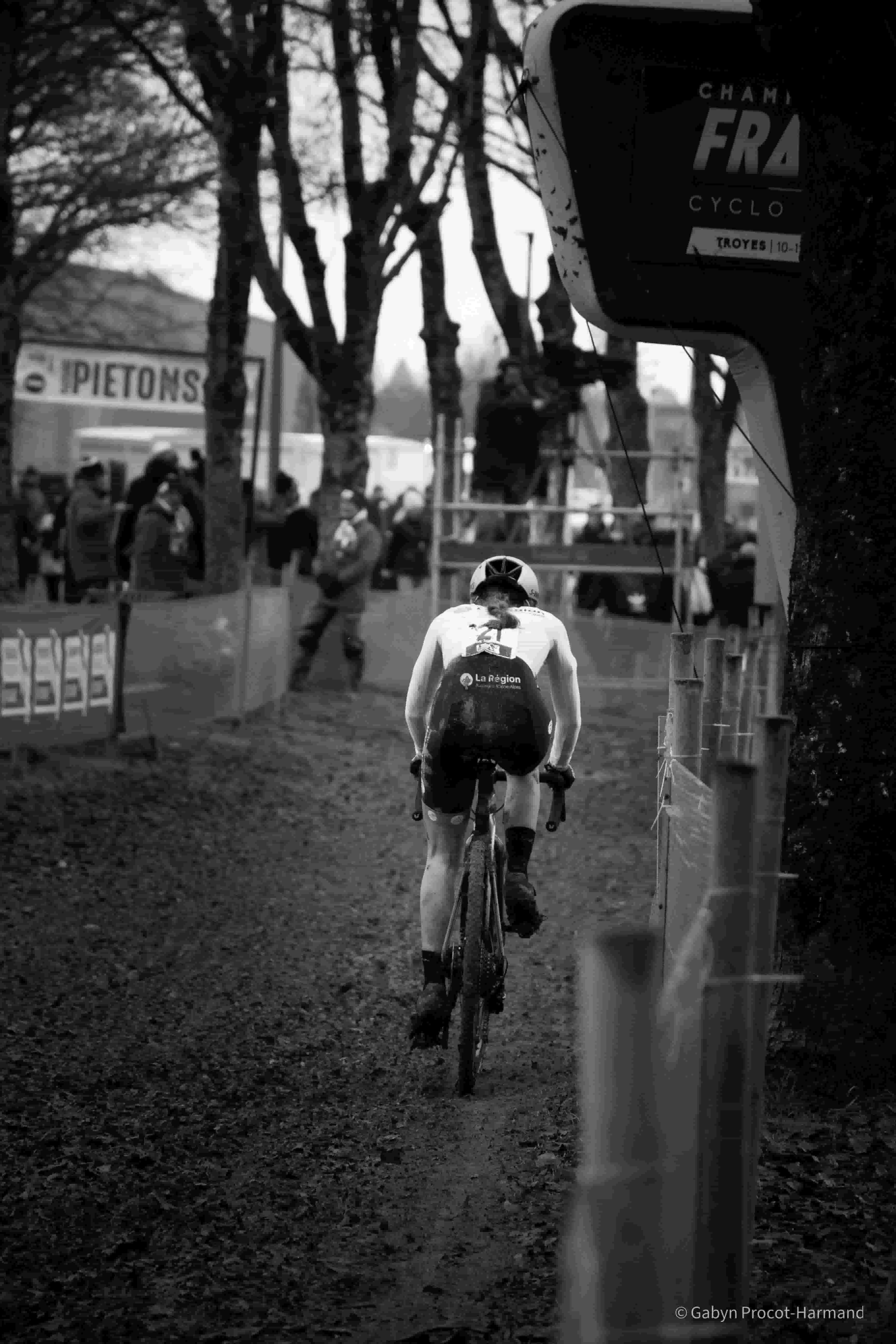 Vue de dos d'une cycliste se dirigeant vers l'arche des Championnats de France